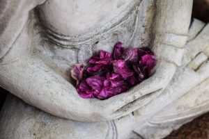Buddha statue with flower petals in his cupped hands