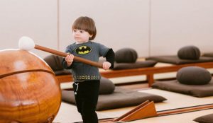 Photo of little boy trying out an instrument in the zendo